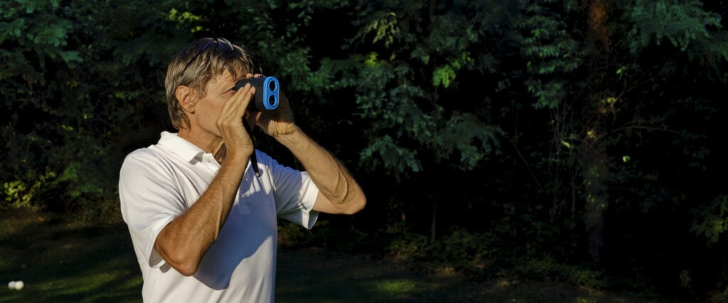 man using a rangefinder on a golf course