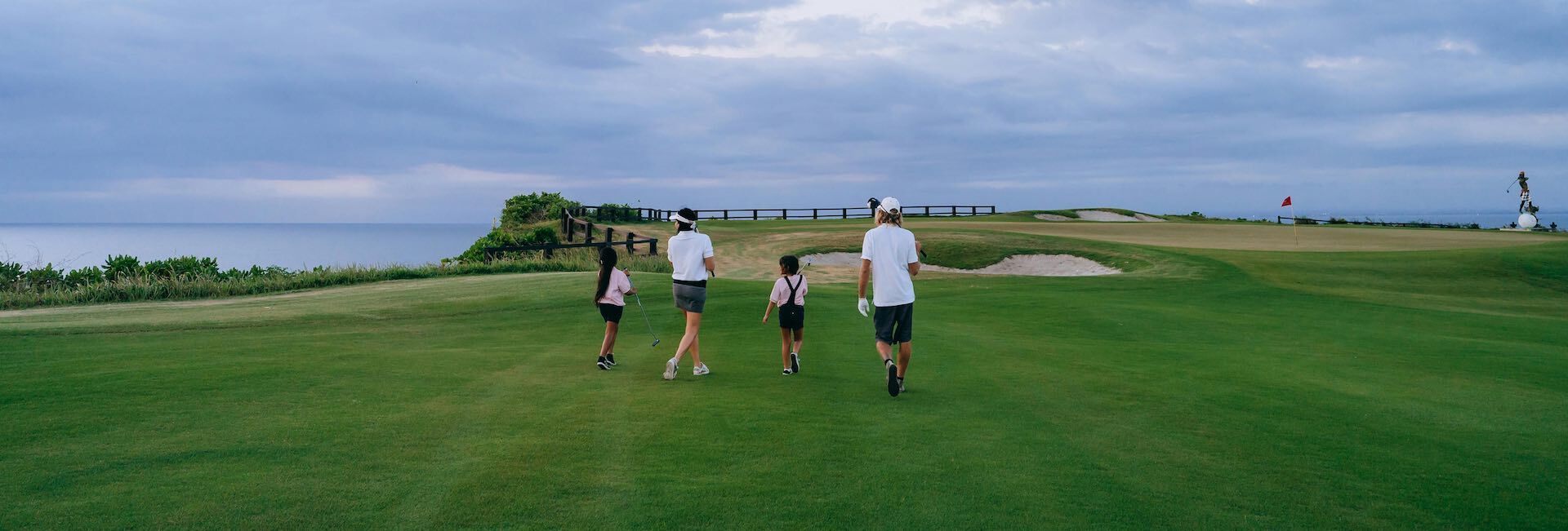 a family of four walking on the golf course